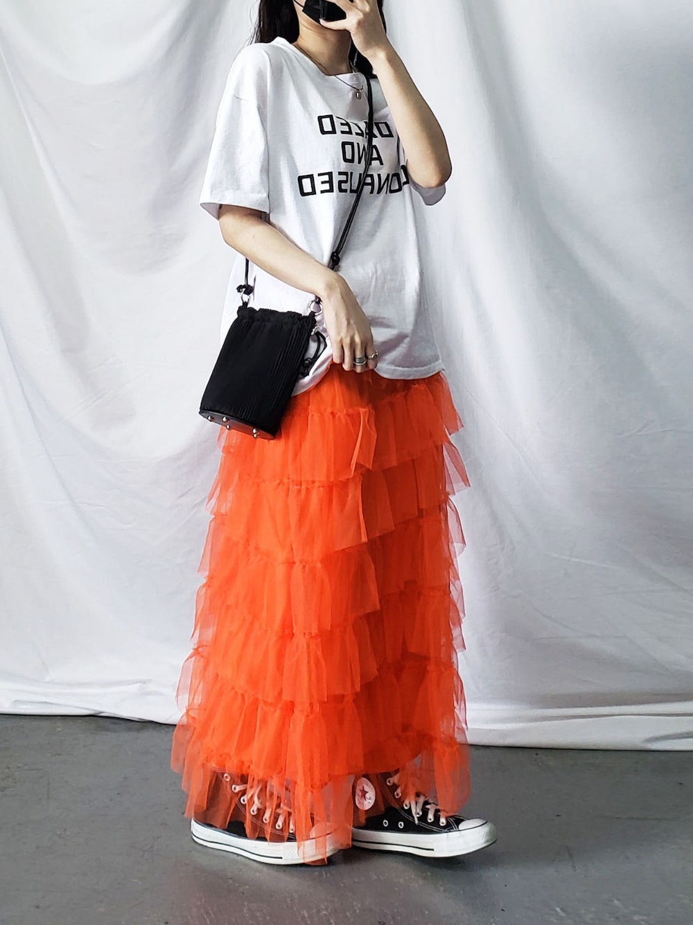 ホワイト系のTシャツ/カットソー、オレンジ系のスカート、ブラック系のショルダーバッグを着用したレディースの春コーディネートの1枚目の写真
