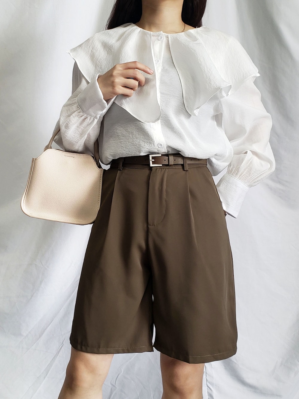 ブラウン系のその他パンツ、ベージュ系のハンドバッグ、ホワイト系のシャツ/ブラウスを着用したレディースの春コーディネートの1枚目の写真