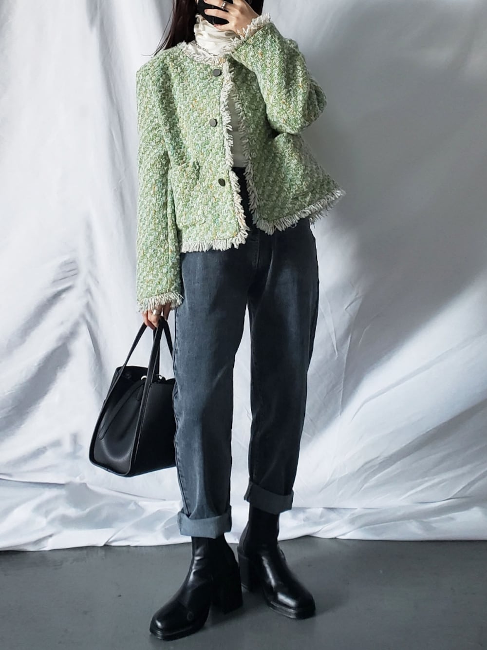 グレー系のデニムパンツ、グリーン系のノーカラージャケット、ブラック系のショルダーバッグを着用したレディースの冬コーディネートの1枚目の写真