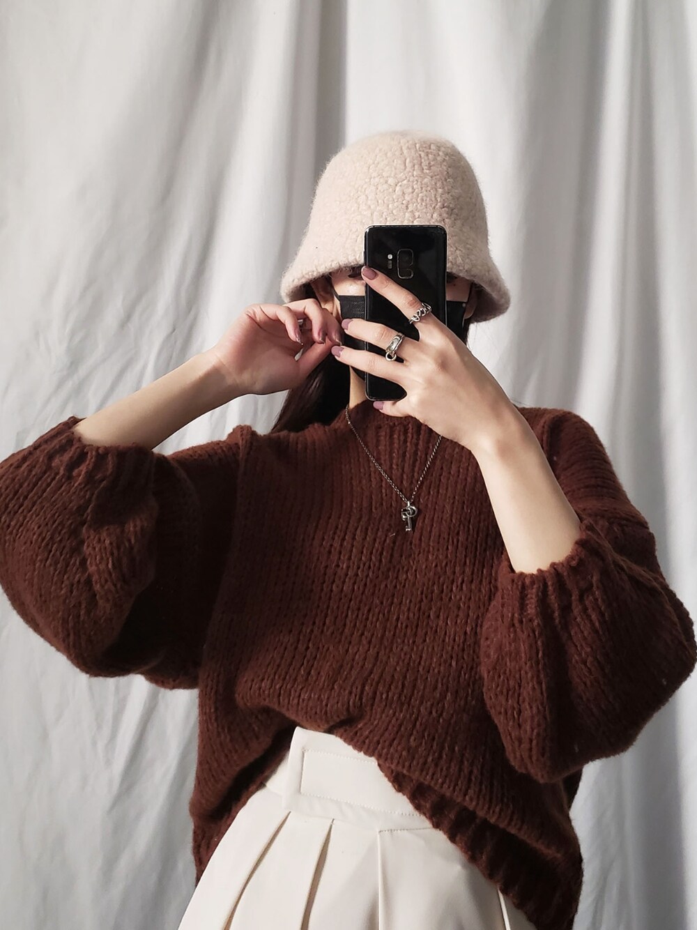 パープル系のニット/セーター、ブラック系のハットを着用したレディースの冬コーディネートの2枚目の写真