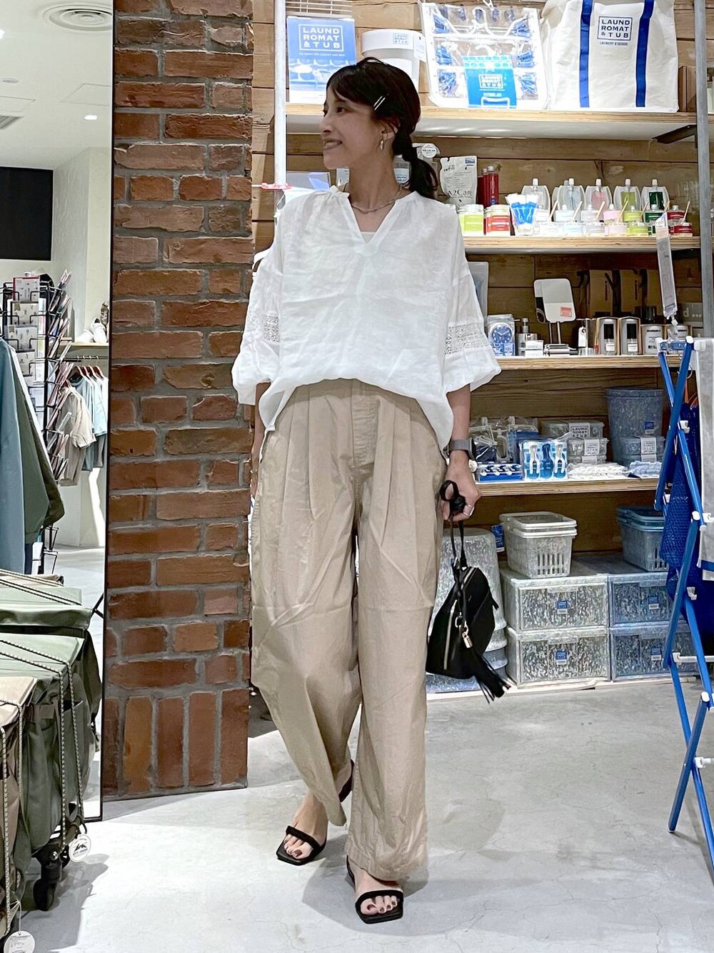 ブラック系のサンダル、ブラック系のショルダーバッグ、ベージュ系のキャミソールを着用したレディースの夏コーディネートの1枚目の写真