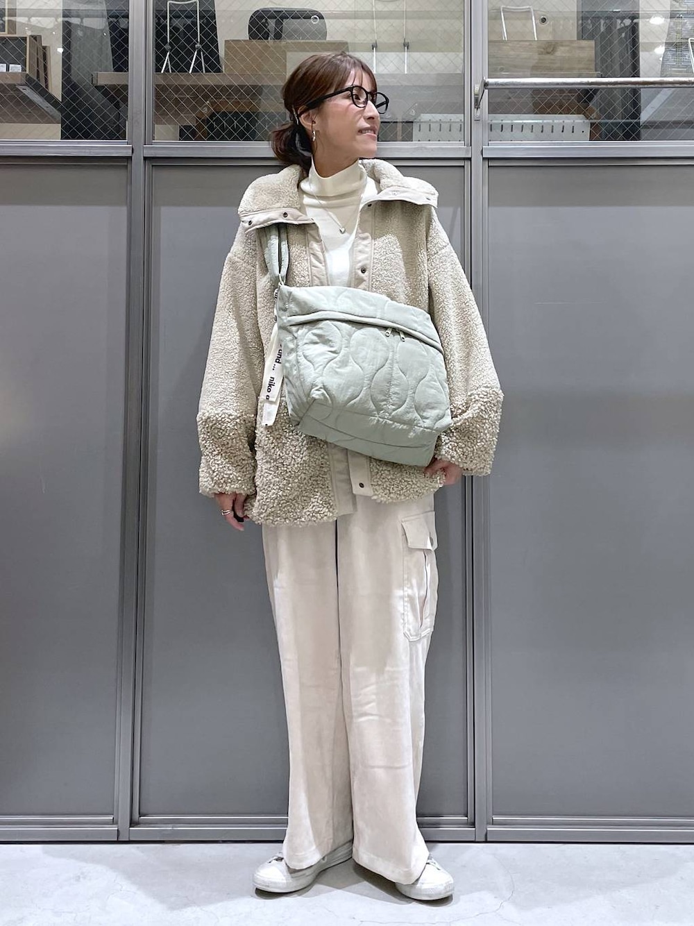 ベージュ系のその他アウター、ベージュ系のニット/セーター、グリーン系のショルダーバッグを着用したレディースの秋コーディネートの1枚目の写真