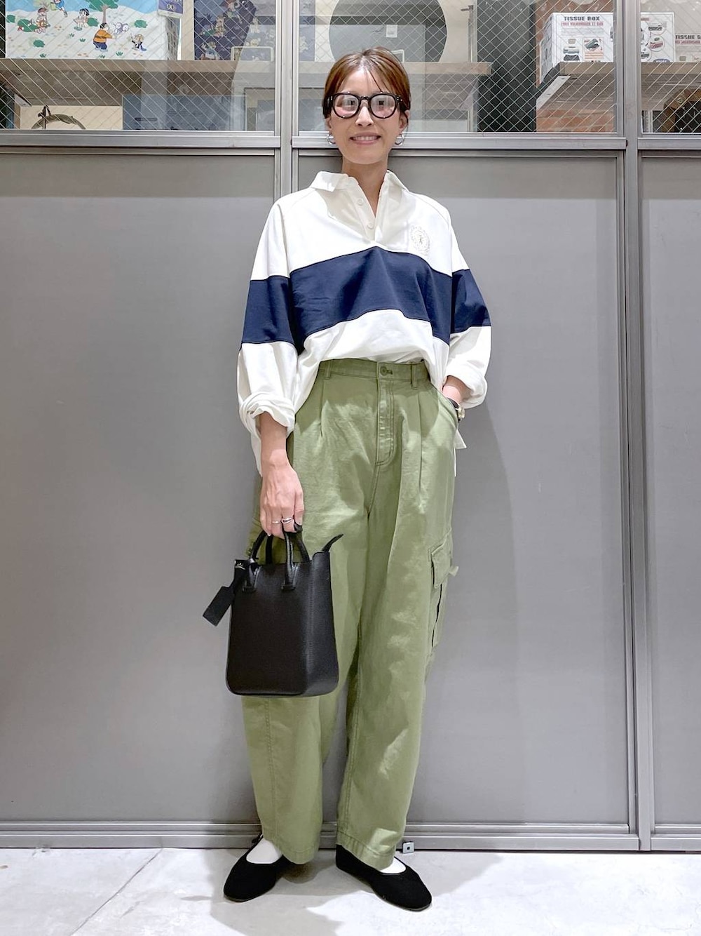 ブラック系のトートバッグ、ブラック系のパンプス、グリーン系のカーゴパンツを着用したレディースの春コーディネートの1枚目の写真