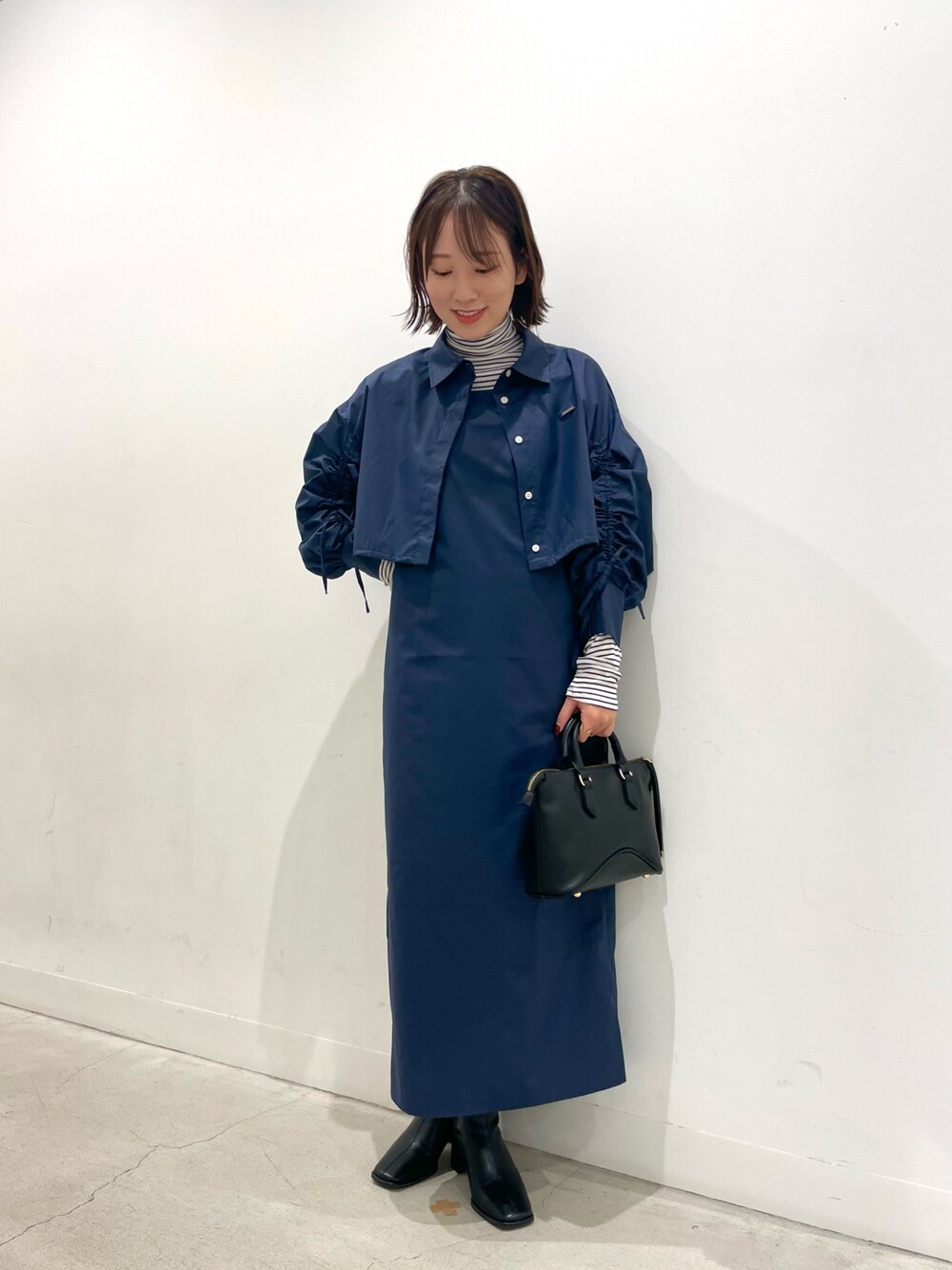 ホワイト系のTシャツ/カットソー、ブルー系のワンピース、ブラック系のブーツを着用したレディースの秋コーディネートの1枚目の写真