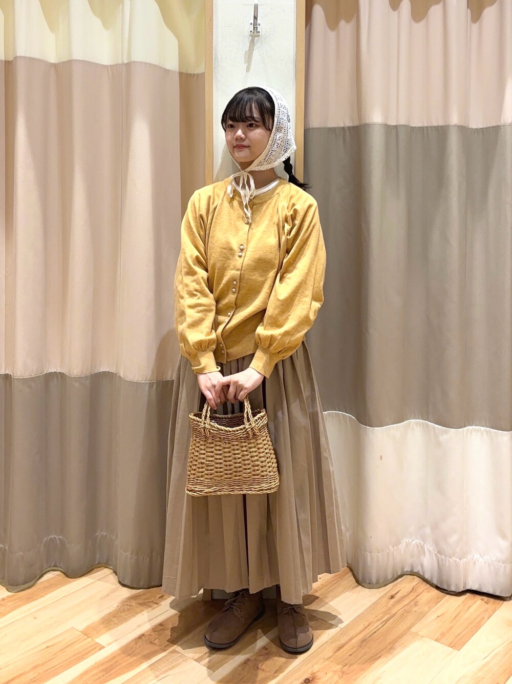 イエロー系のカーディガン/ボレロ、ベージュ系のスカート、ベージュ系のドレスシューズを着用したレディースの秋コーディネートの1枚目の写真