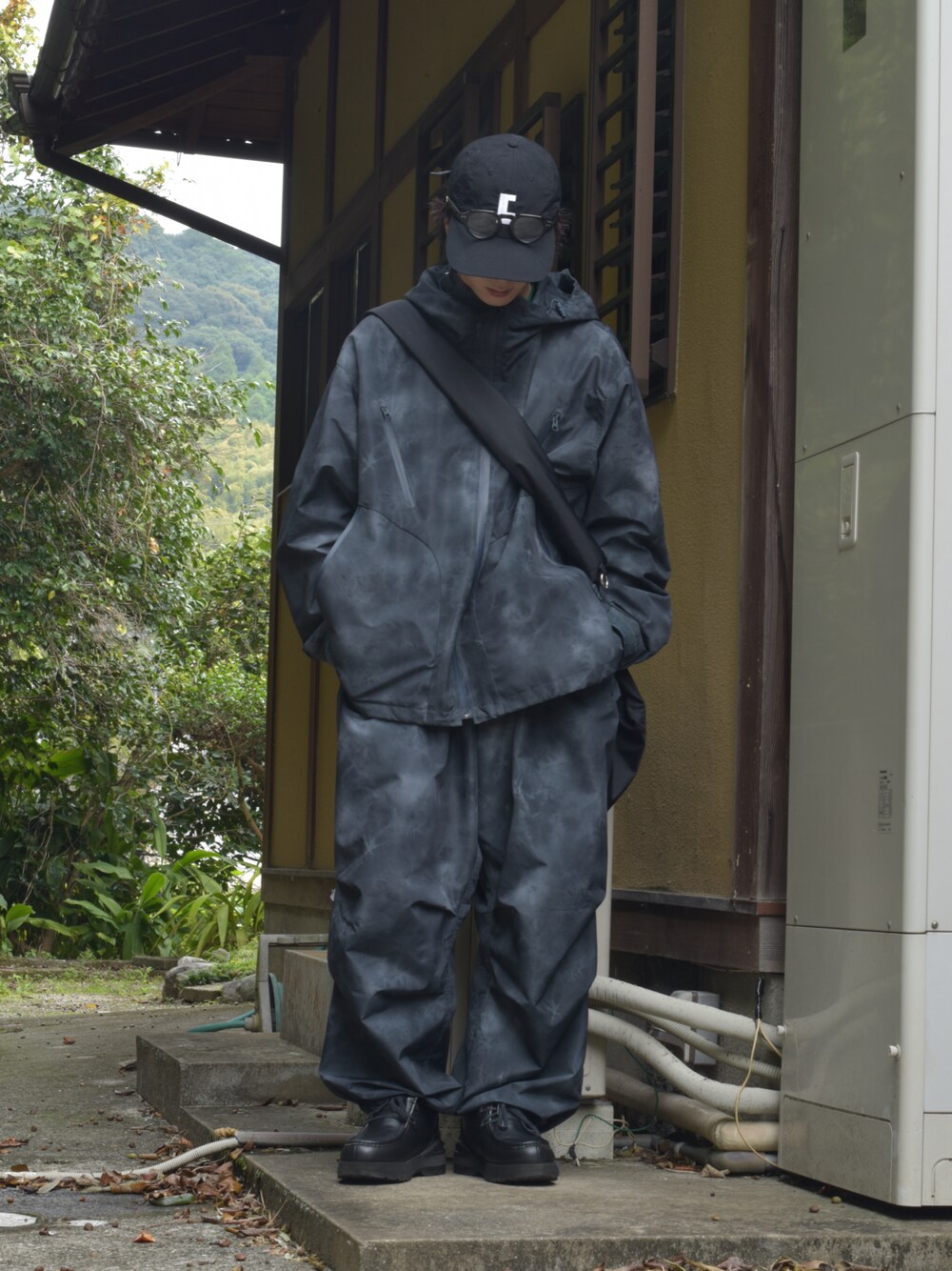 「セットアップ、パーカー、カーゴパンツ、キャップ、メガネ男子、厚底シューズ、ショルダーバッグ、雨の日コーデ、低身長、お出かけコーデ、スニーカー、モノトーン、韓国ファッション、冬コーデ、冬アウター」｜「soerteのTotal pattern loose mountain parker （Water-repellent ）/トータルパターンルーズマウンテンパーカー（撥水加工）（マウンテンパーカー、ブラック系）」を使った、熊谷一平さん（骨格ウェーブ・メンズ・165cm）の秋コーディネートの1枚目の写真