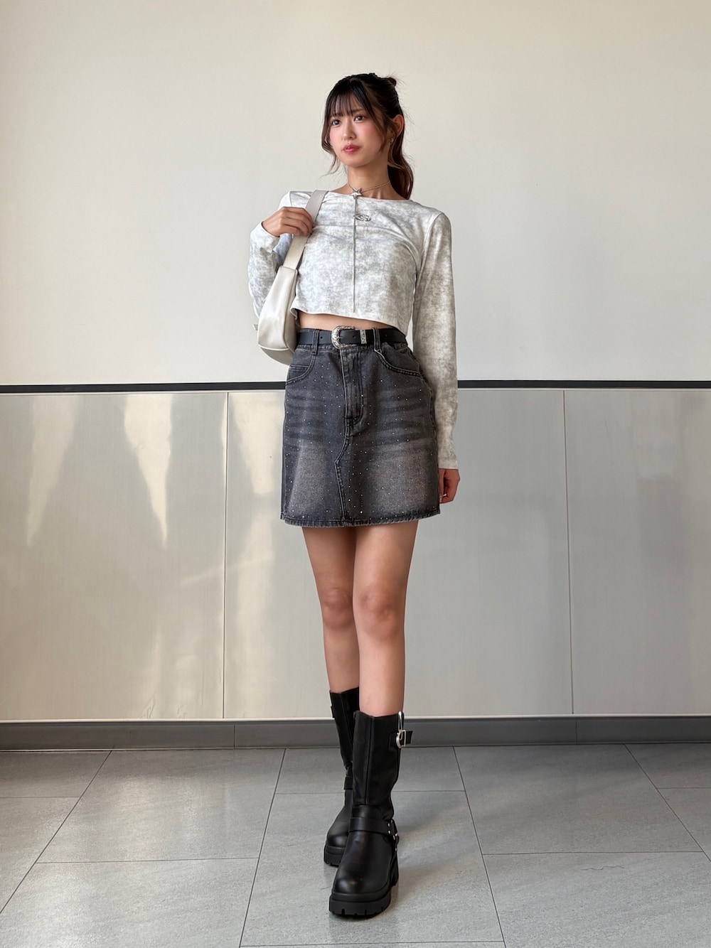 ホワイト系のTシャツ/カットソー、グレー系のデニムスカート、ブラック系のブーツを着用したレディースの秋コーディネートの1枚目の写真