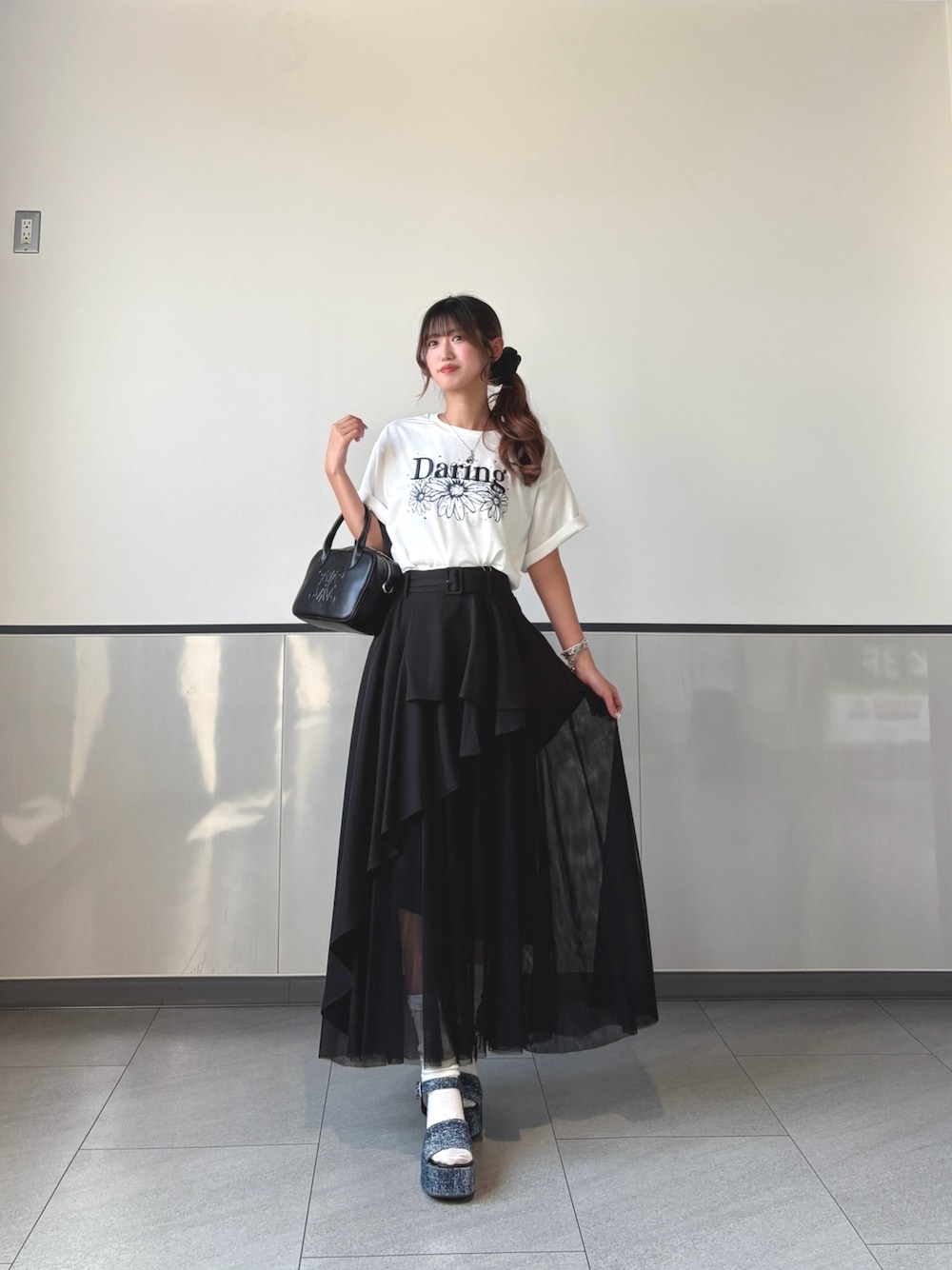 ブラック系のスカート、ホワイト系のTシャツ/カットソー、ブラック系のハンドバッグを着用したレディースの秋コーディネートの1枚目の写真