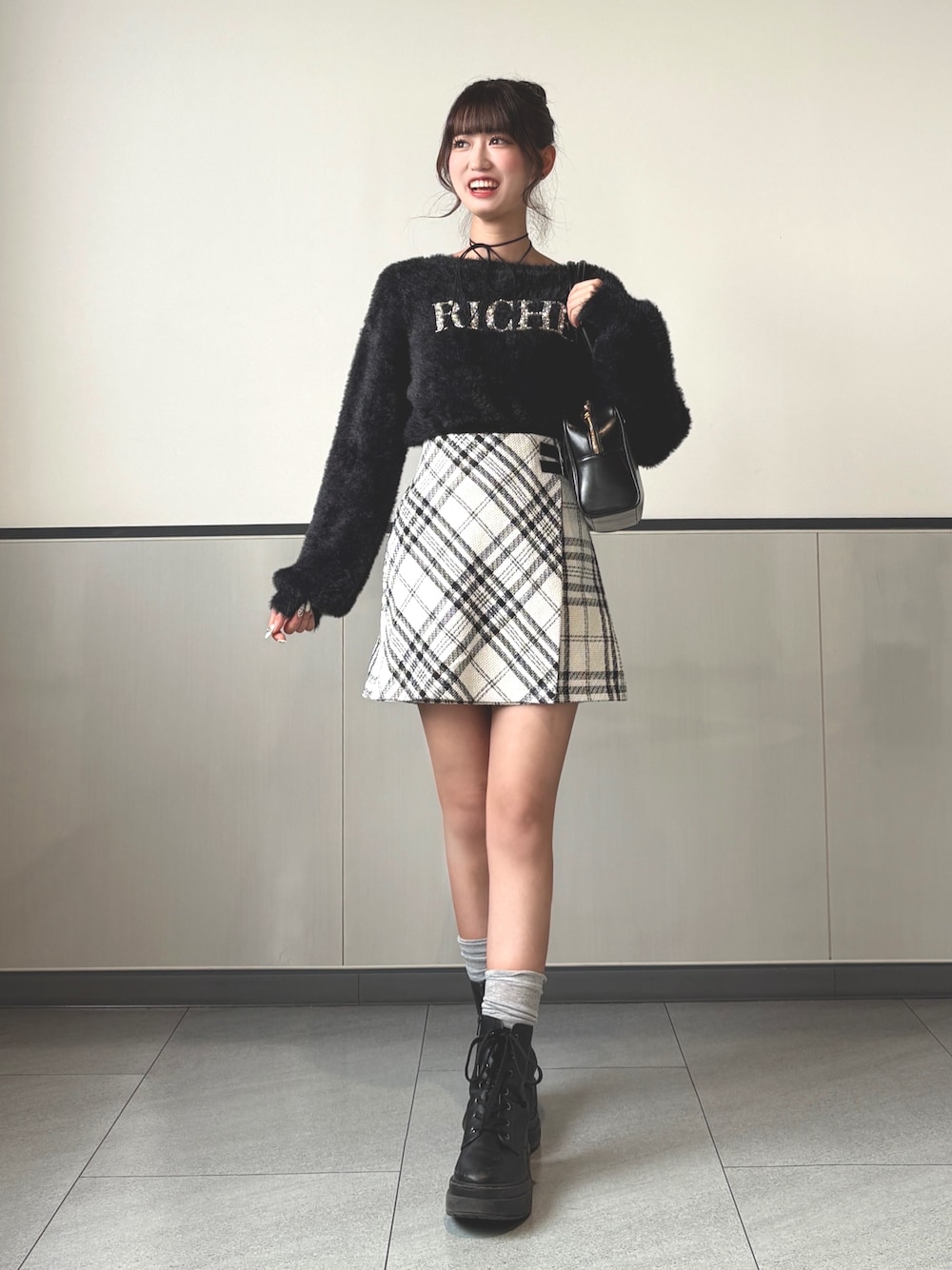 ブラック系のニット/セーター、ブラック系のハンドバッグ、ホワイト系のスカートを着用したレディースの秋コーディネートの1枚目の写真