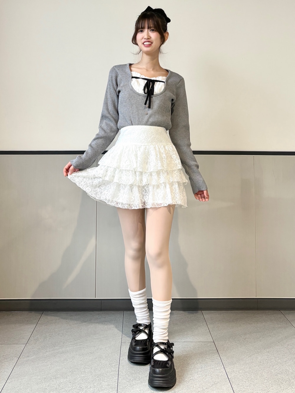 グレー系のニット/セーター、ホワイト系のスカートを着用したレディースの冬コーディネートの1枚目の写真