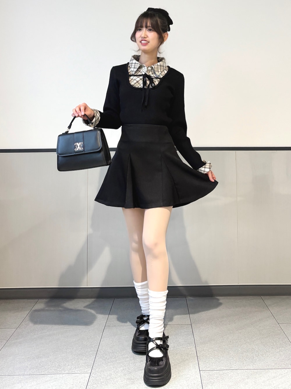 ブラック系のニット/セーター、ブラック系のスカート、ブラック系のハンドバッグを着用したレディースの冬コーディネートの1枚目の写真