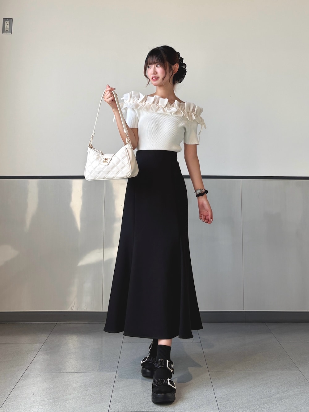 ブラック系のスカート、ホワイト系のショルダーバッグ、ホワイト系のニット/セーターを着用したレディースの秋コーディネートの1枚目の写真