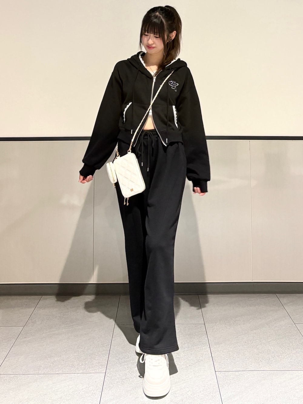 ブラック系のパーカー、ブラック系のスウェットパンツ、ホワイト系のスニーカーを着用したレディースの春コーディネートの1枚目の写真