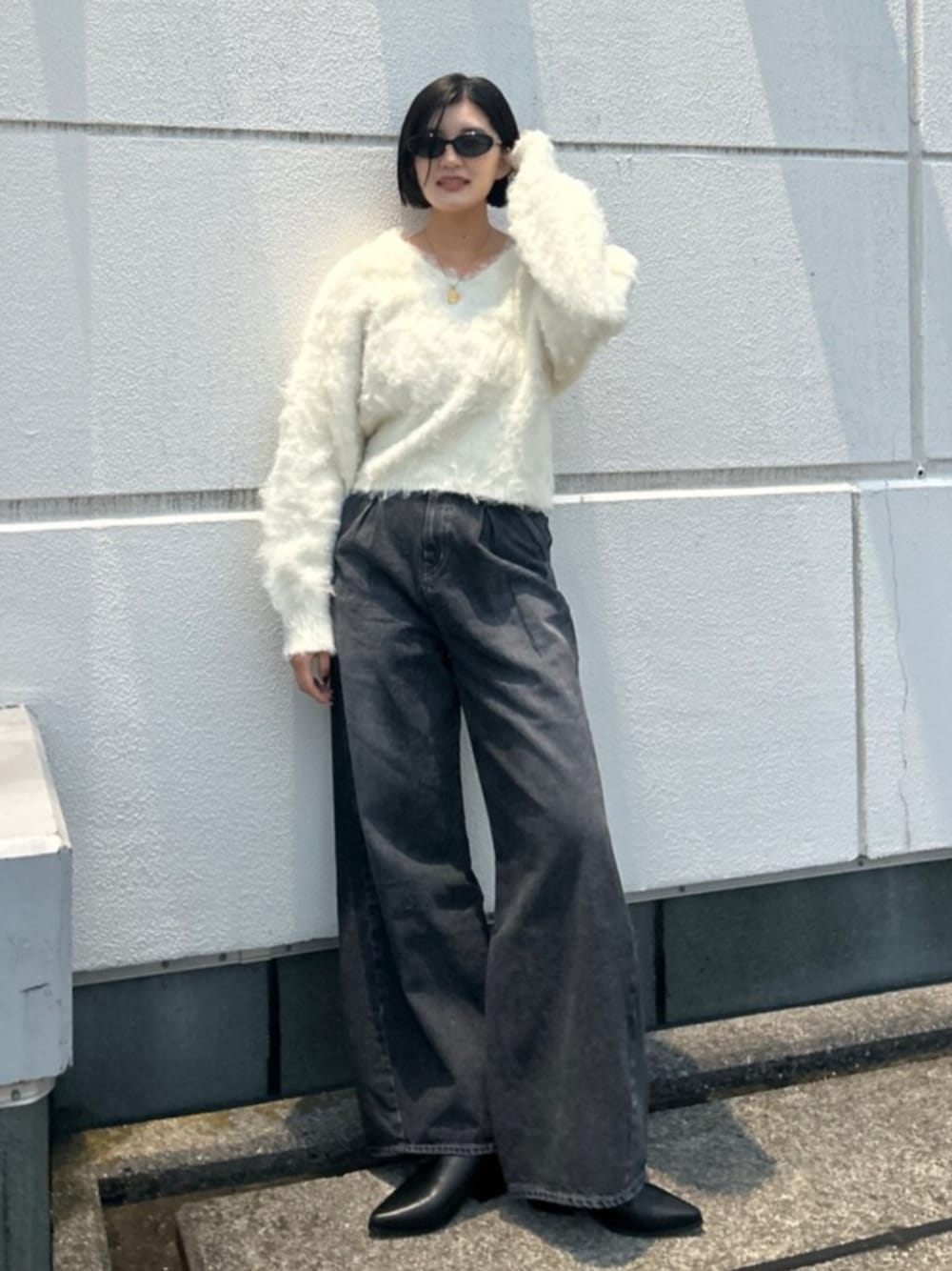 ホワイト系のニット/セーター、ブラック系のデニムパンツ、ブラック系のブーツを着用したレディースの秋コーディネートの1枚目の写真