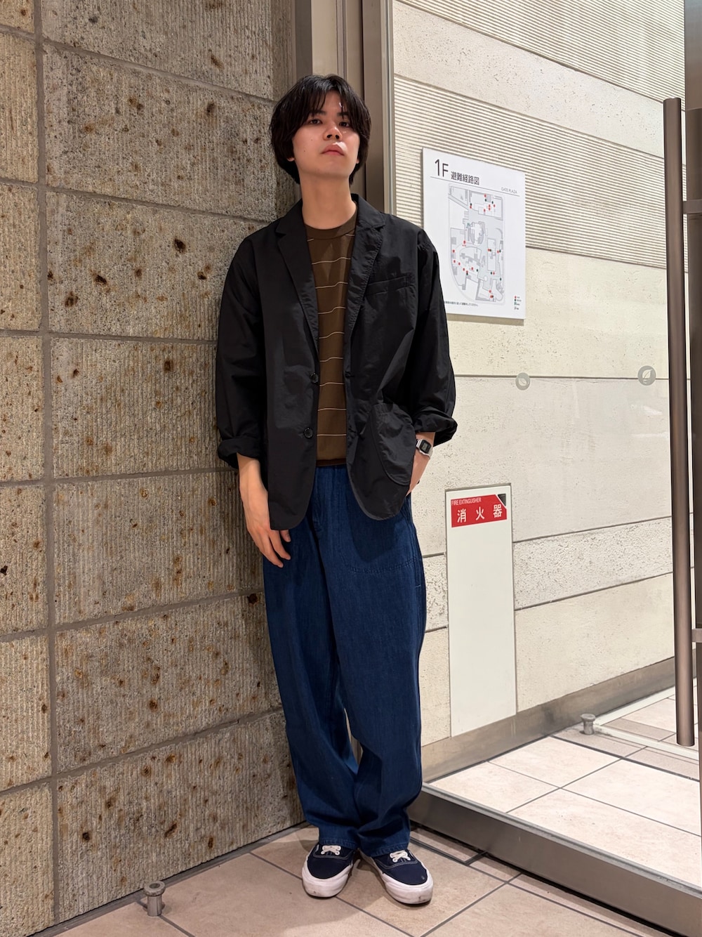 ブラック系のその他アウター、ブラウン系のニット/セーター、ブルー系のデニムパンツを着用したメンズの春コーディネートの1枚目の写真
