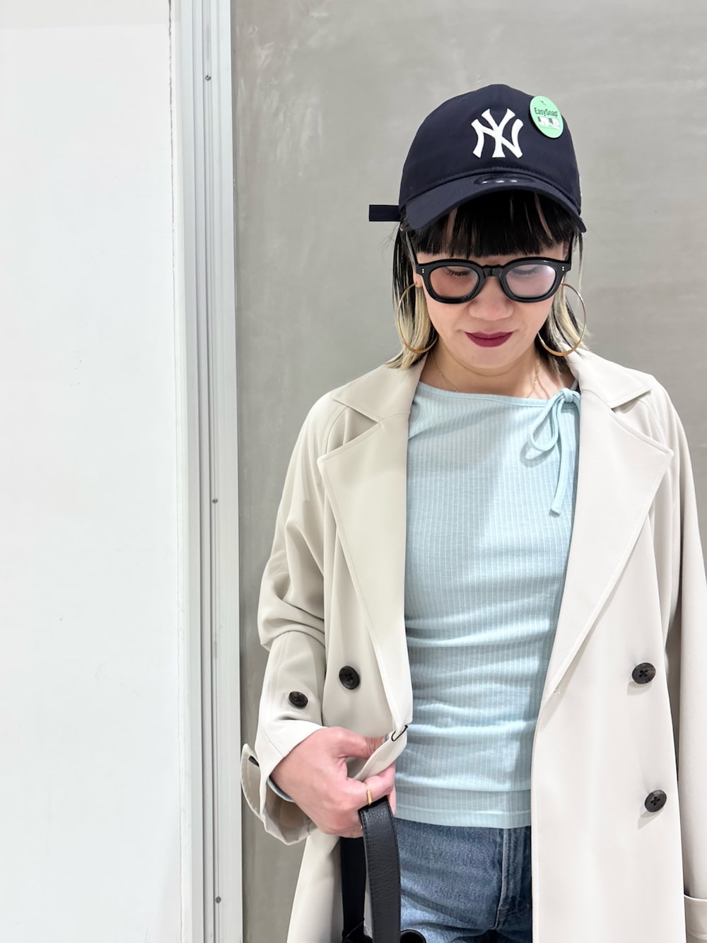 ブルー系のデニムパンツ、ブラック系のハンドバッグ、ブラウン系のスニーカーを着用したレディースの春コーディネートの1枚目の写真