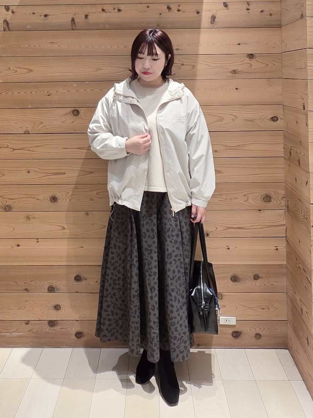 ホワイト系のマウンテンパーカー、ベージュ系のニット/セーター、ブラック系のボストンバッグを着用したレディースの冬コーディネートの1枚目の写真