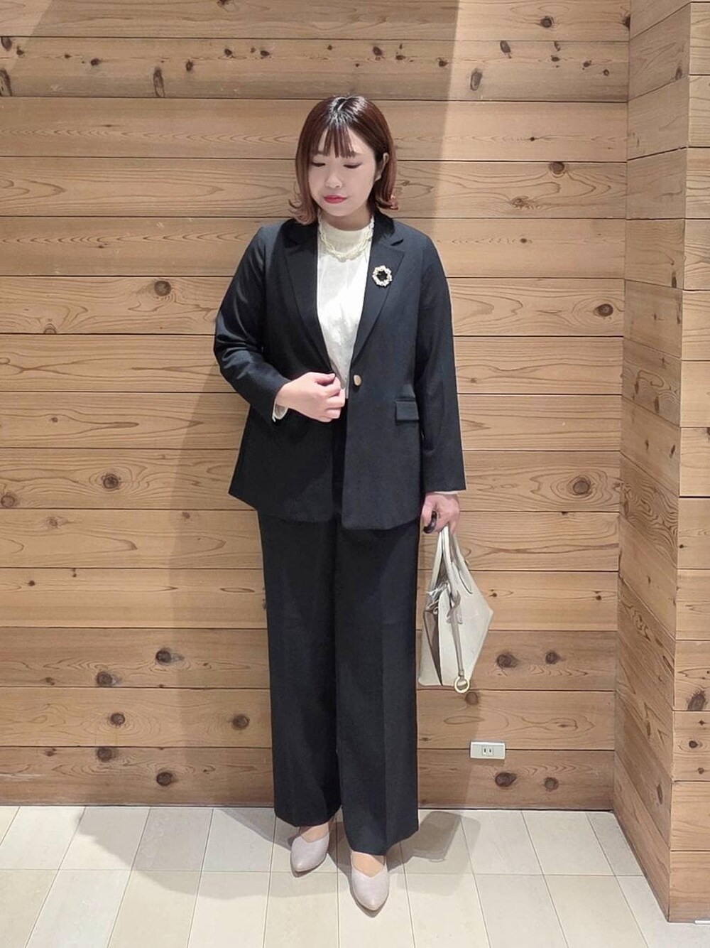 ホワイト系のショルダーバッグ、ホワイト系のパンプス、ブルー系のスラックスを着用したレディースの冬コーディネートの1枚目の写真
