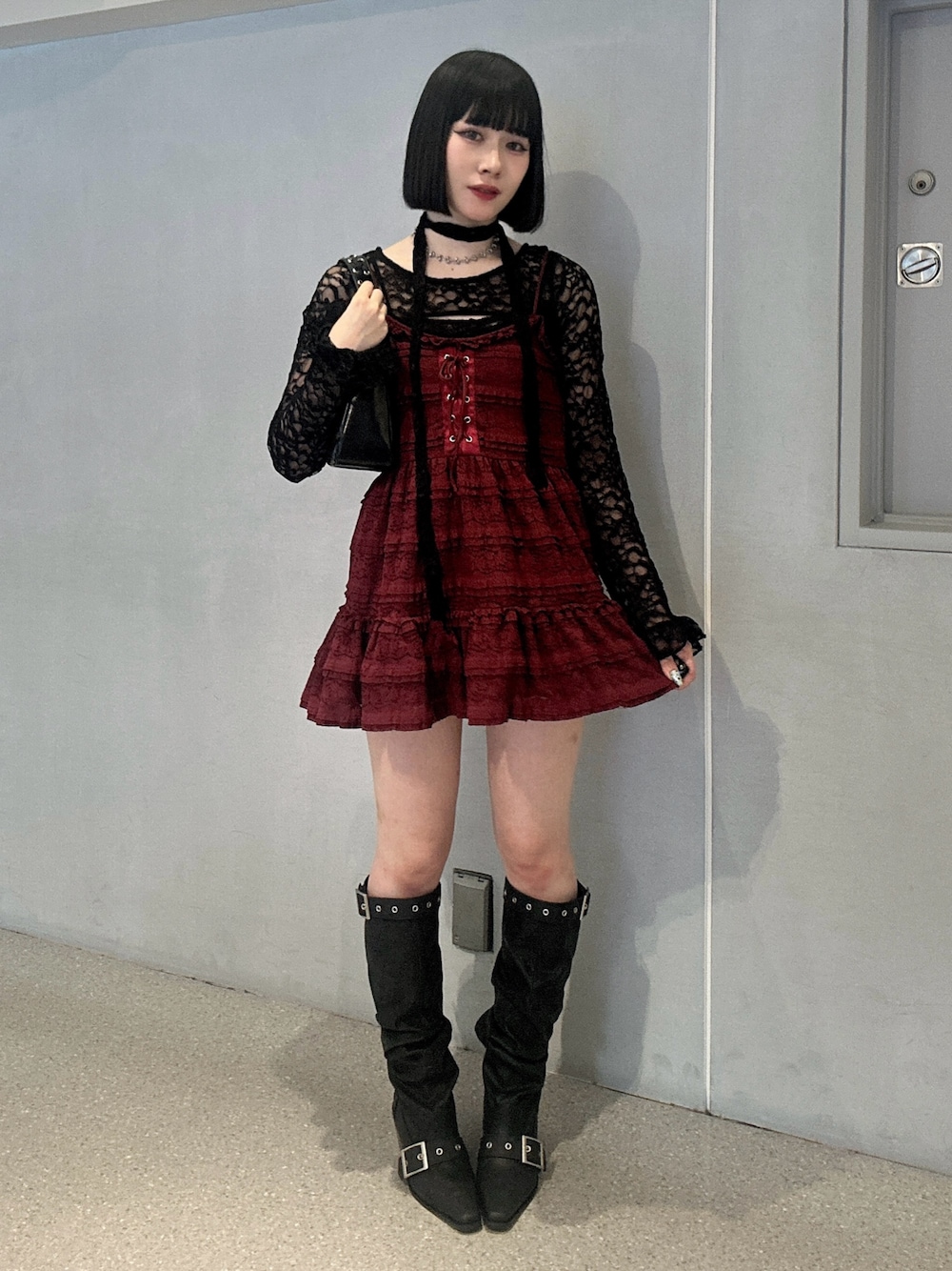 レッド系のワンピース、ブラック系のTシャツ/カットソー、ブラック系のブーツを着用したレディースの冬コーディネートの1枚目の写真