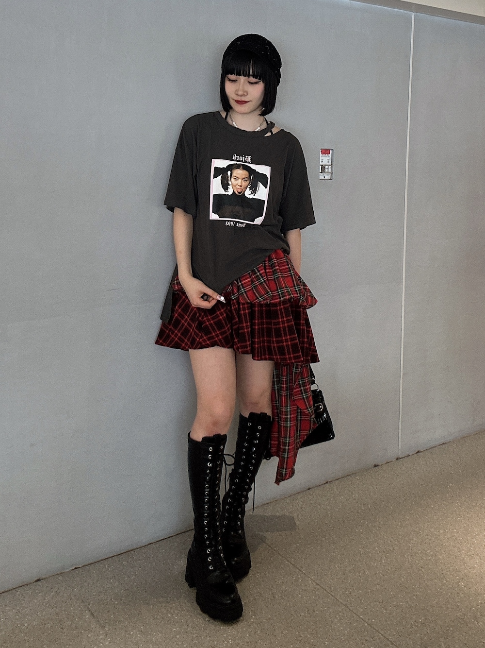 ブラック系のTシャツ/カットソー、レッド系のスカート、ブラック系のブーツを着用したレディースの春コーディネートの1枚目の写真