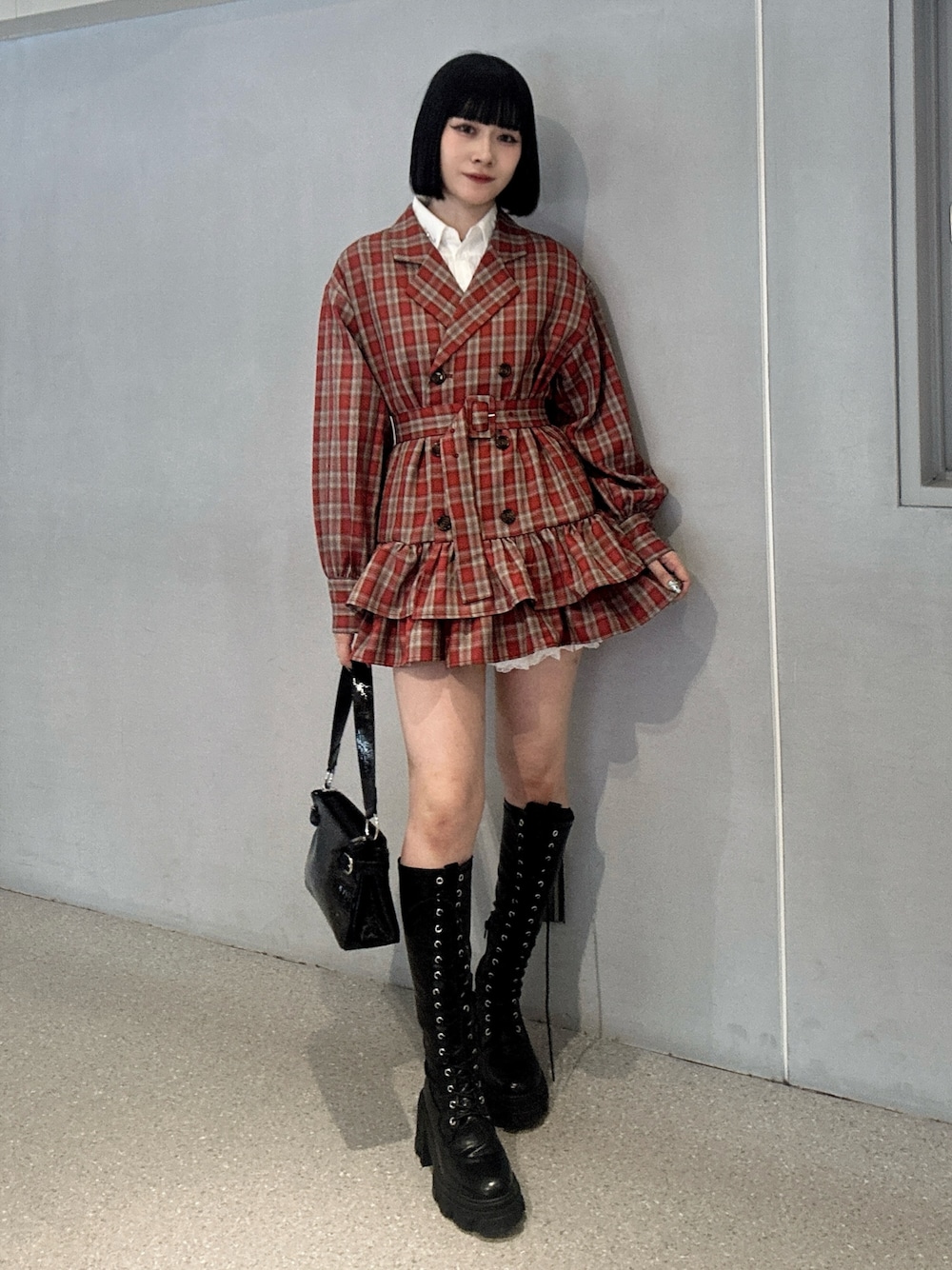 レッド系のワンピース、ブラック系のブーツ、ブラック系のハンドバッグを着用したレディースの冬コーディネートの1枚目の写真