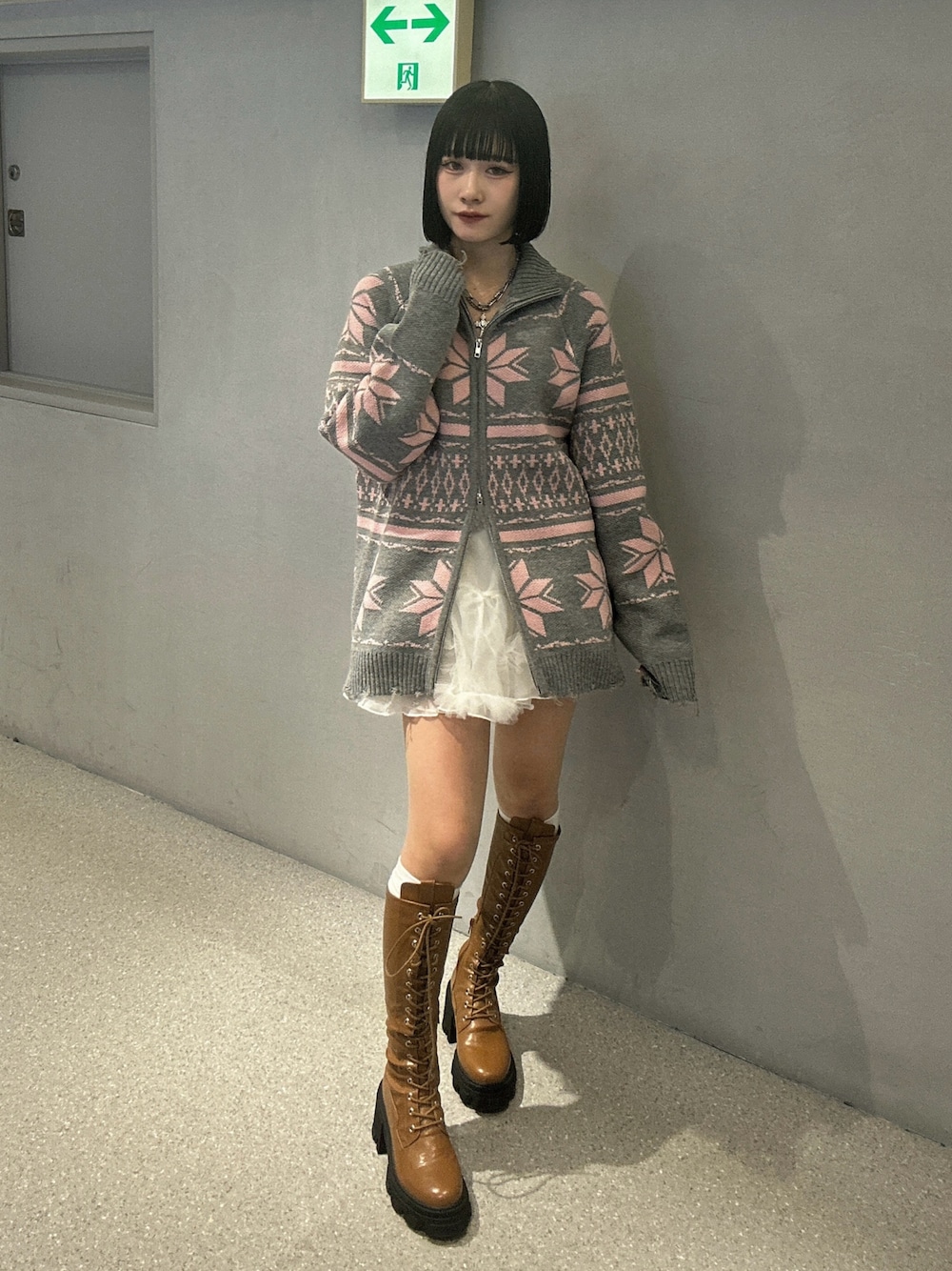 グレー系のカーディガン/ボレロ、ホワイト系のスカート、ブラウン系のブーツを着用したレディースの秋コーディネートの1枚目の写真