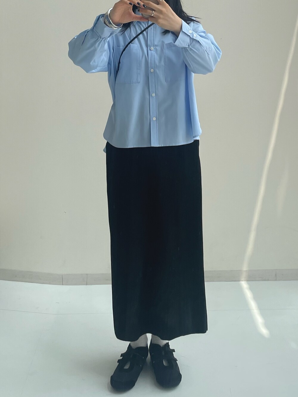 ブラック系のスカート、ブラック系のバレエシューズ、ブルー系のシャツ/ブラウスを着用したレディースの秋コーディネートの1枚目の写真