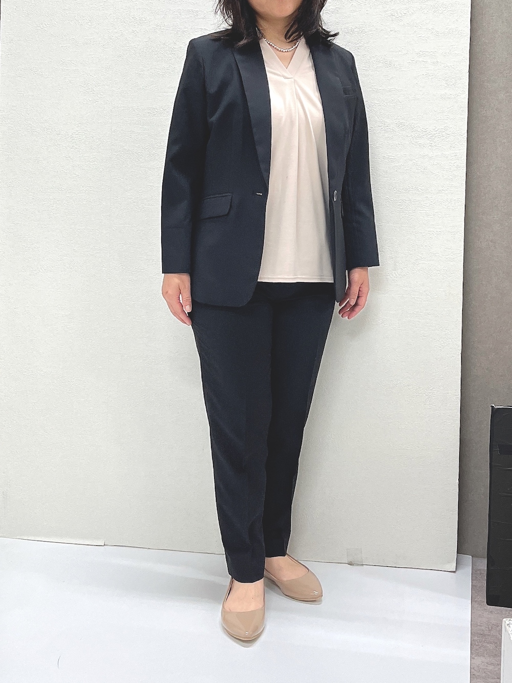 ベージュ系のTシャツ/カットソー、ブラック系のスーツセット、ベージュ系のパンプスを着用したレディースの夏コーディネートの1枚目の写真