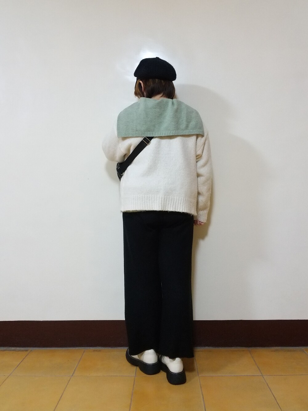 グリーン系のニット/セーター、ホワイト系のカーディガン/ボレロ、ブラック系のパンツを着用したレディースの冬コーディネートの3枚目の写真