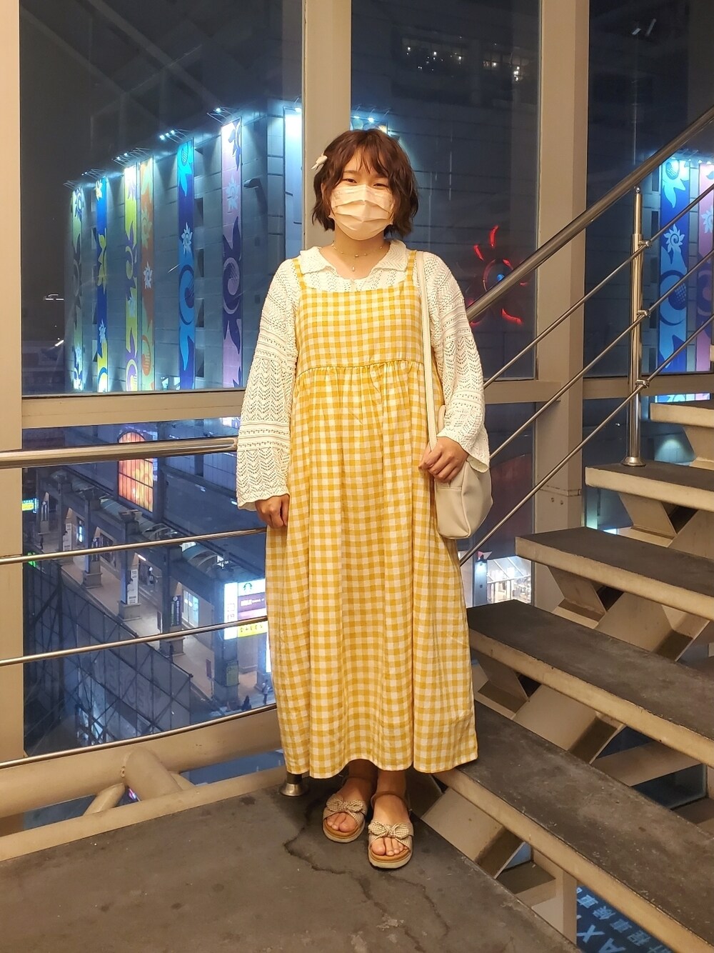 オレンジ系のワンピース、ホワイト系のカーディガン/ボレロ、ブラウン系のサンダルを着用したレディースの春コーディネートの1枚目の写真