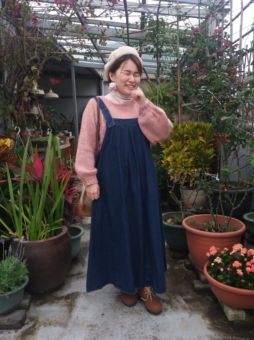 ピンク系のニット/セーター、ベージュ系のトップス、ブルー系のジャンパースカートを着用したレディースの冬コーディネートの2枚目の写真