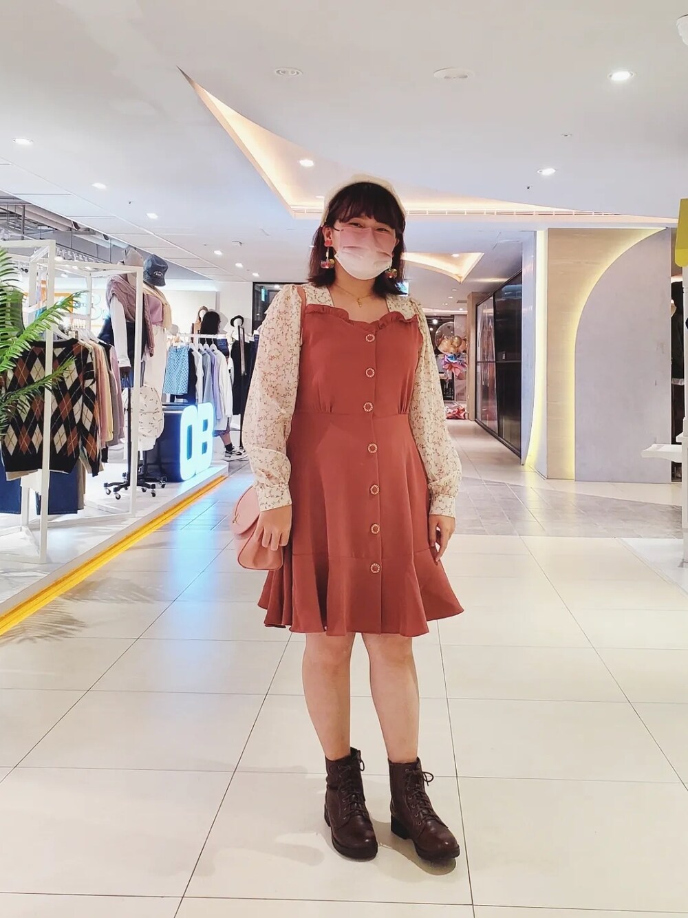 レッド系のシャツワンピース、ブラウン系のブーツ、ピンク系のショルダーバッグを着用したレディースの冬コーディネートの1枚目の写真