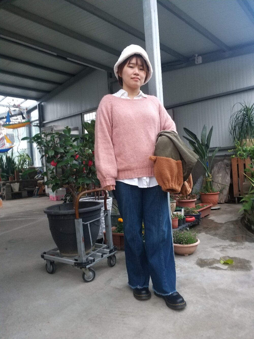 ピンク系のニット/セーター、ホワイト系のシャツ/ブラウス、グリーン系のジャケット/アウターを着用したレディースの冬コーディネートの2枚目の写真