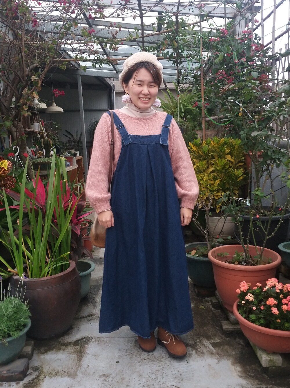 ピンク系のニット/セーター、ベージュ系のトップス、ブルー系のジャンパースカートを着用したレディースの冬コーディネートの3枚目の写真