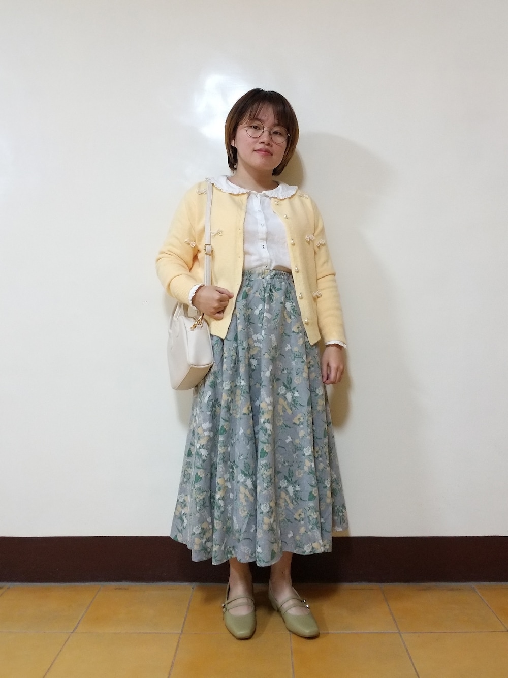 ホワイト系のシャツ/ブラウス、イエロー系のカーディガン/ボレロ、イエロー系のスカートを着用したレディースの春コーディネートの2枚目の写真