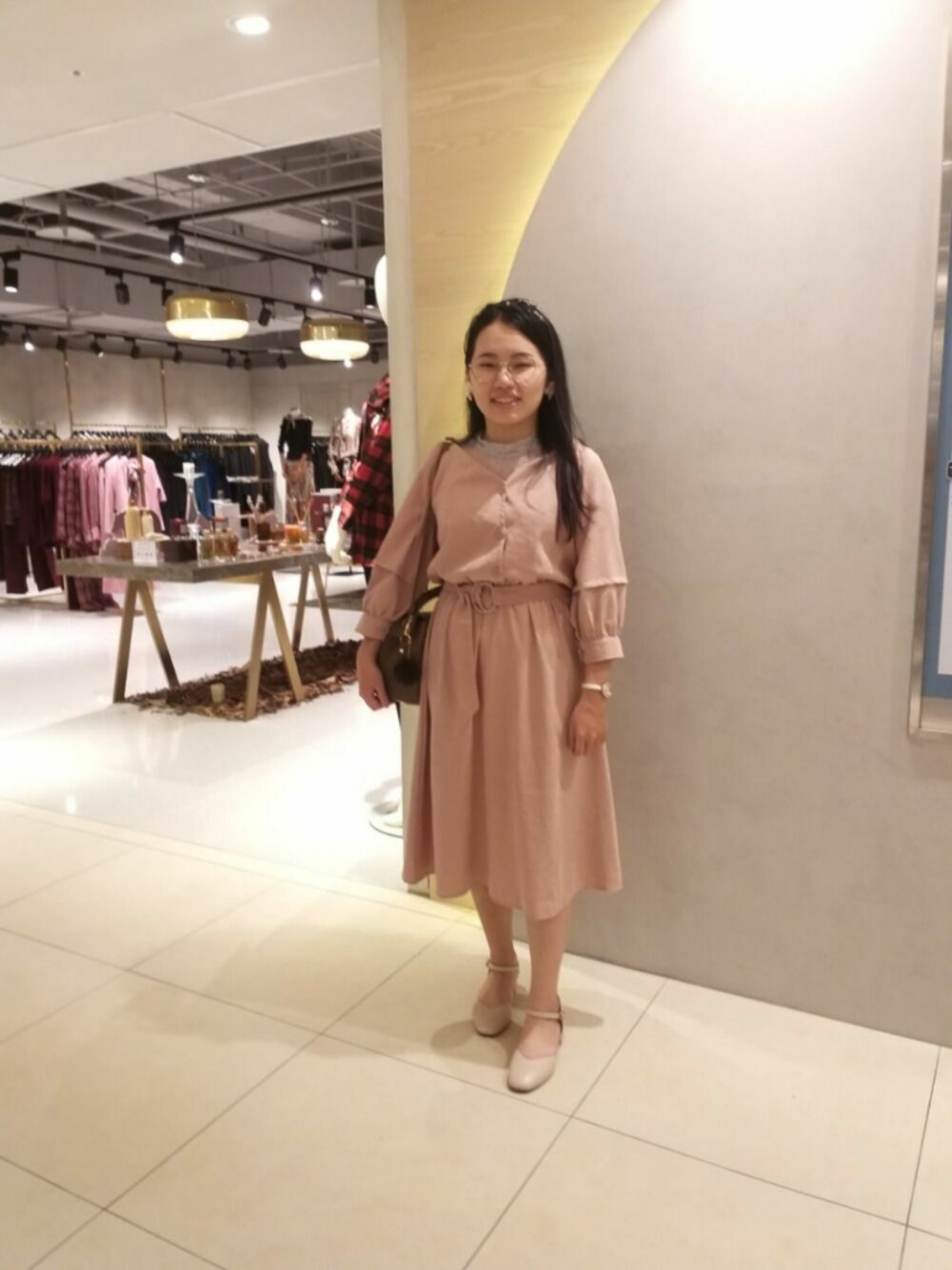 ピンク系のワンピース、グレー系のトップス、ピンク系のシューズを着用したレディースの春コーディネートの1枚目の写真