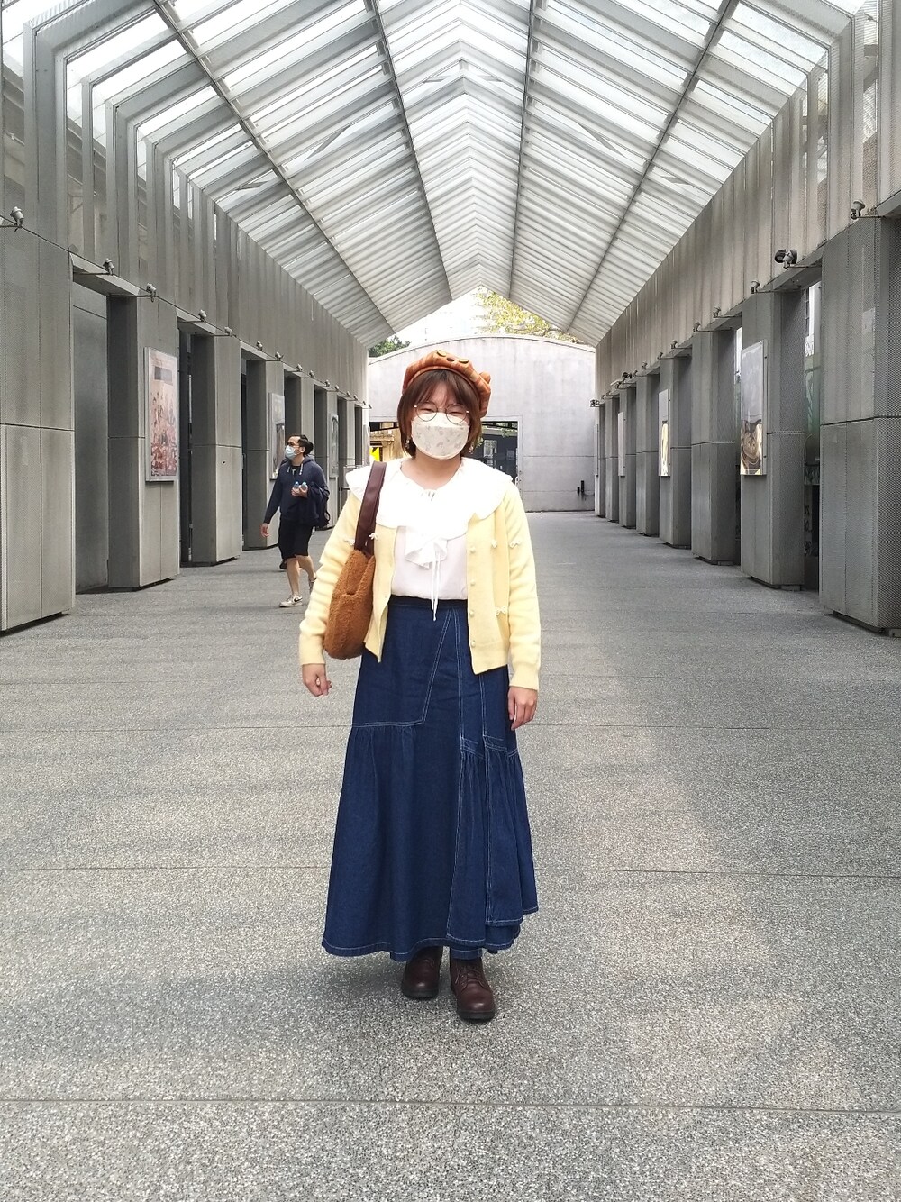 ホワイト系のシャツ/ブラウス、イエロー系のカーディガン/ボレロ、ブルー系のデニムスカートを着用したレディースの春コーディネートの2枚目の写真