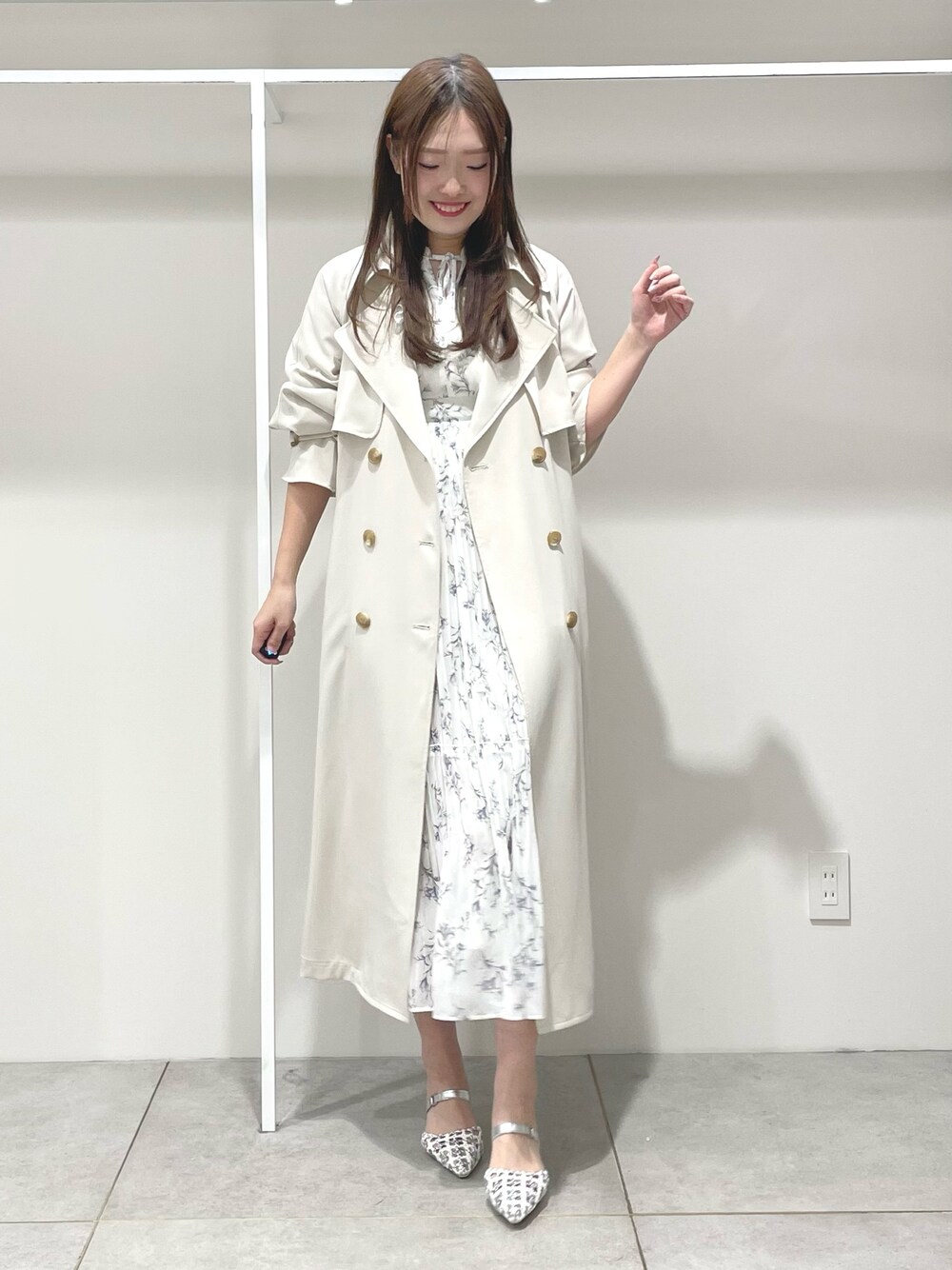 ホワイト系のトレンチコート、ホワイト系のワンピース、シルバー系のパンプスを着用したレディースの春コーディネートの1枚目の写真