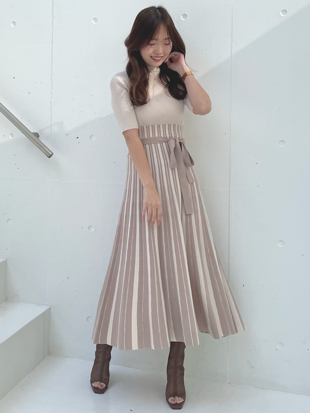 ベージュ系のワンピース、ブラウン系のブーツを着用したレディースの春コーディネートの1枚目の写真