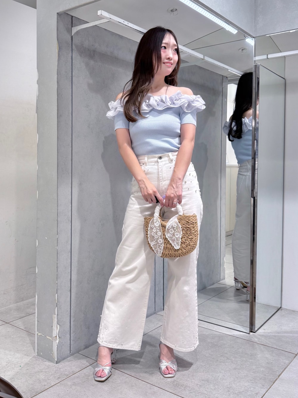 ブルー系のニット/セーター、ベージュ系のハンドバッグ、ホワイト系のデニムパンツを着用したレディースの夏コーディネートの1枚目の写真