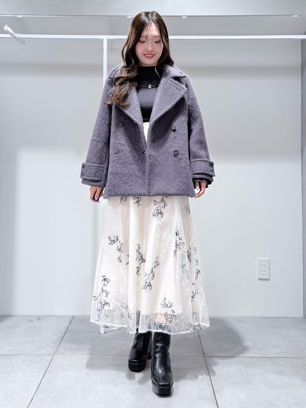 グレー系のその他アウター、グレー系のニット/セーター、ホワイト系のスカートを着用したレディースの冬コーディネートの1枚目の写真