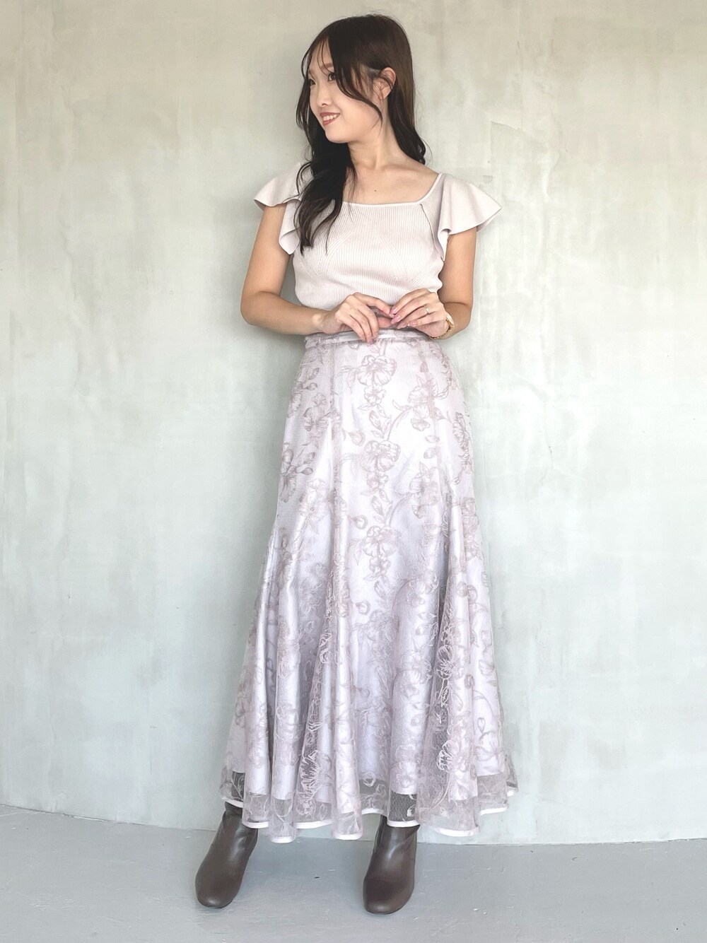 ピンク系のニット/セーター、ピンク系のスカート、ブラウン系のブーツを着用したレディースの春コーディネートの1枚目の写真