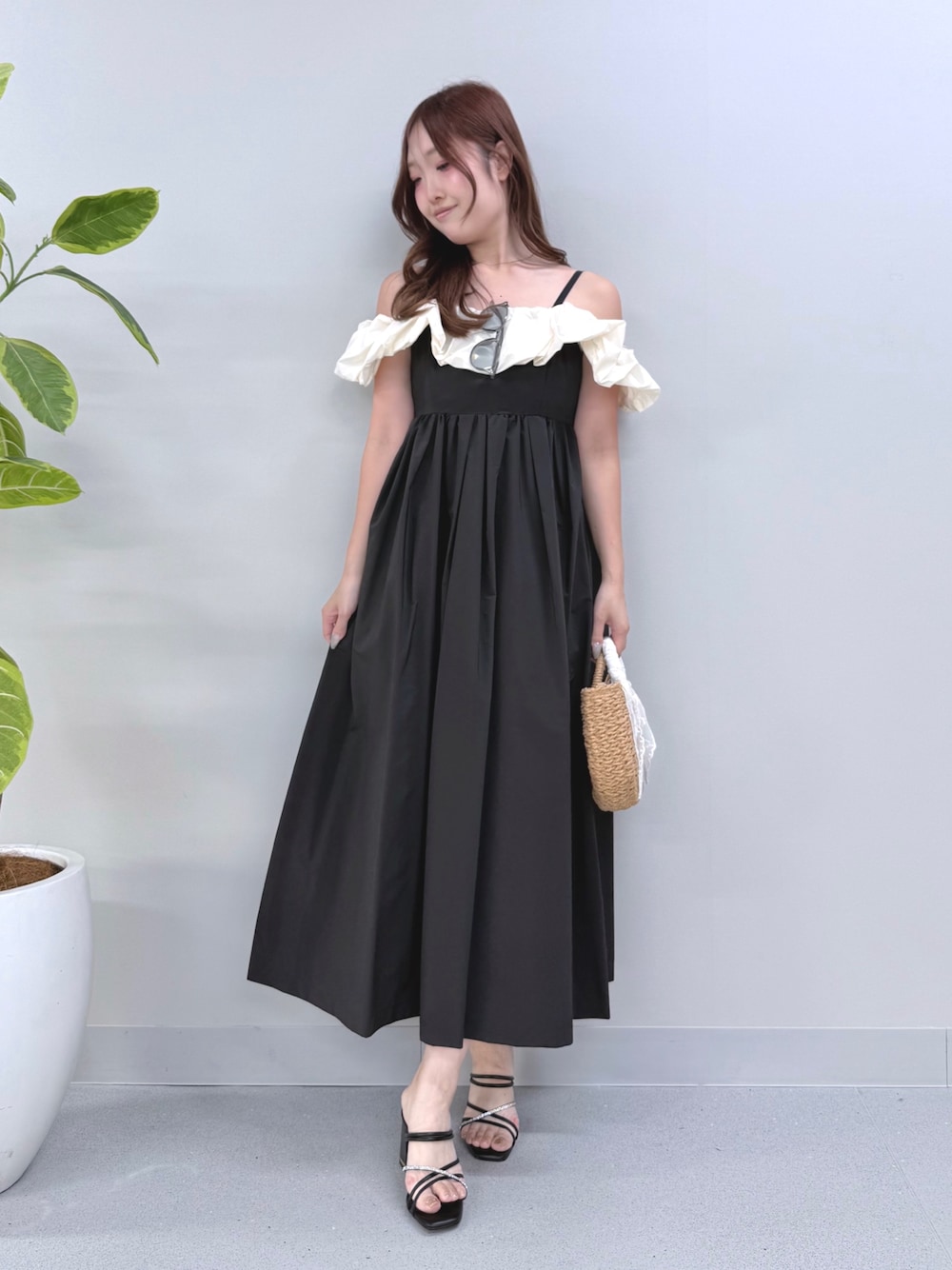 ブラック系のワンピース、ベージュ系のハンドバッグ、ブラック系のサンダルを着用したレディースの夏コーディネートの1枚目の写真