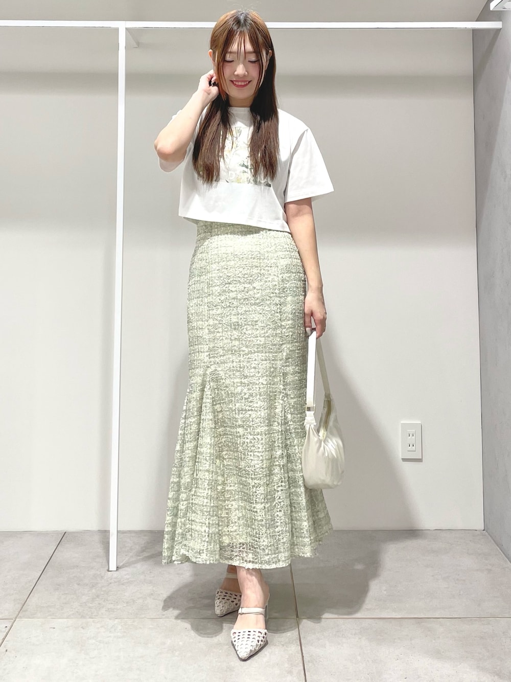 ホワイト系のTシャツ/カットソー、ホワイト系のショルダーバッグ、グリーン系のスカートを着用したレディースの春コーディネートの1枚目の写真