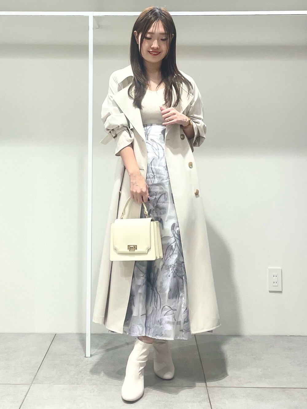 ホワイト系のトレンチコート、ホワイト系のハンドバッグ、パープル系のワンピースを着用したレディースの春コーディネートの1枚目の写真