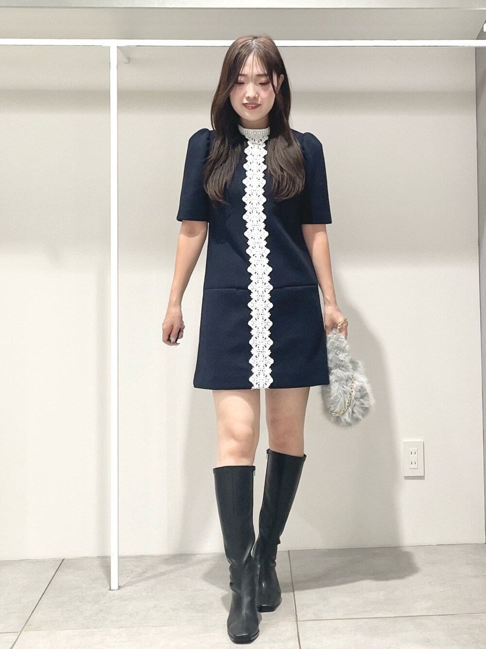 ブルー系のワンピース、ブラック系のブーツ、グレー系のハンドバッグを着用したレディースの秋コーディネートの1枚目の写真