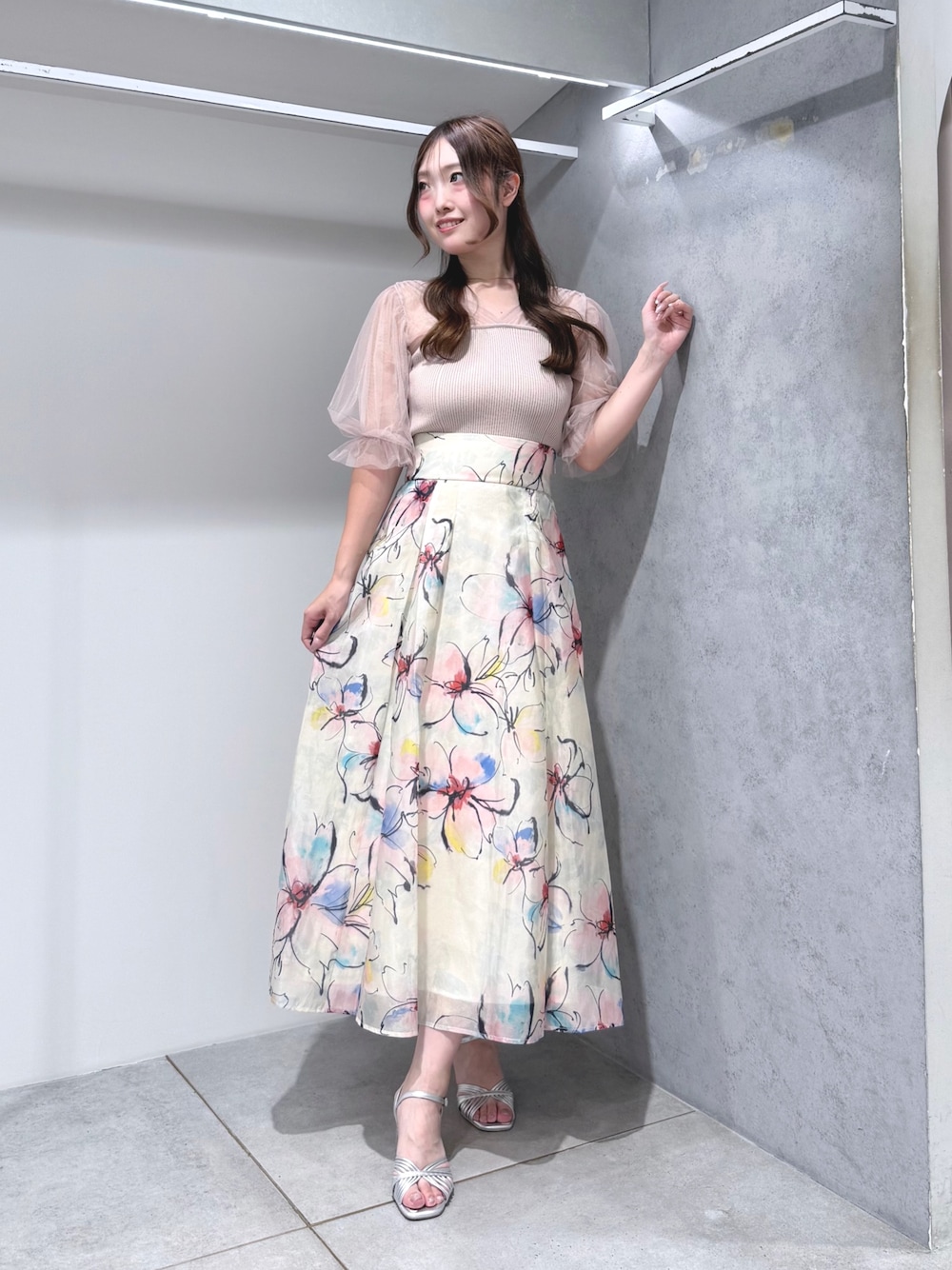 ピンク系のニット/セーター、ホワイト系のスカート、シルバー系のサンダルを着用したレディースの夏コーディネートの1枚目の写真