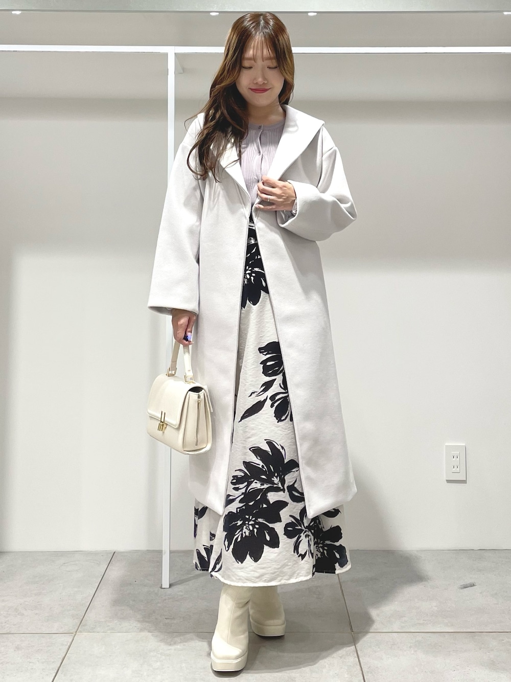 ホワイト系のスカート、ホワイト系のチェスターコート、ベージュ系のカーディガン/ボレロを着用したレディースの秋コーディネートの1枚目の写真