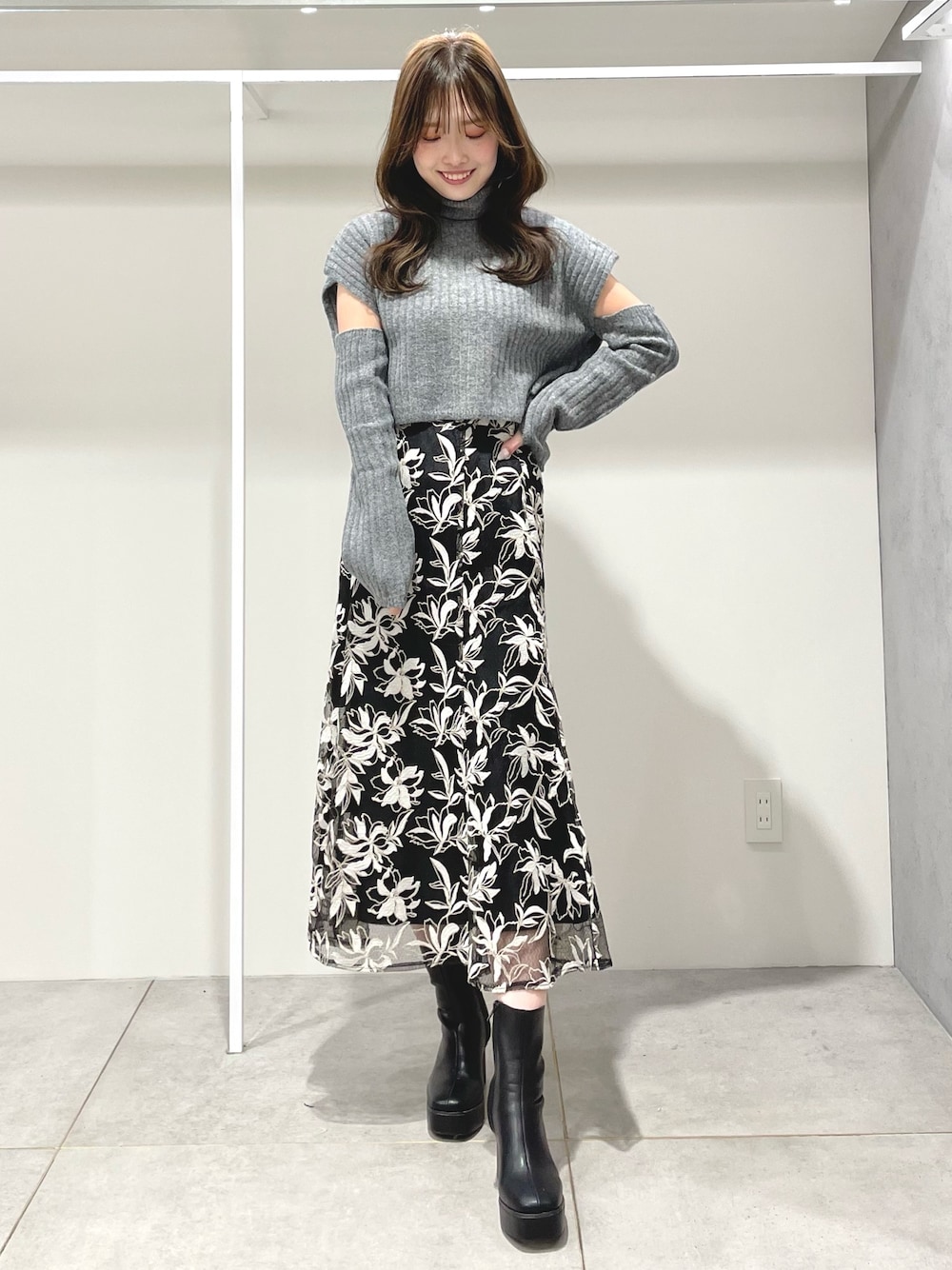 ブラック系のスカート、ブラック系のブーツ、グレー系のニット/セーターを着用したレディースの冬コーディネートの1枚目の写真