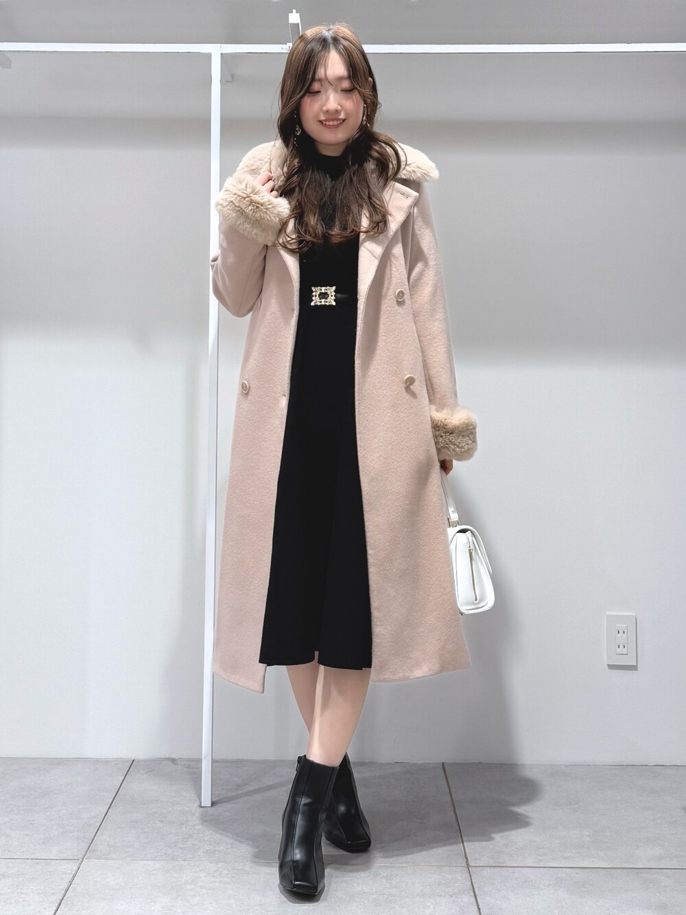 ベージュ系のその他アウター、ホワイト系のハンドバッグ、ブラック系のワンピースを着用したレディースの冬コーディネートの1枚目の写真